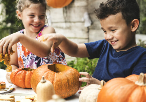Young kids carving Halloween jack-o-lanterns
